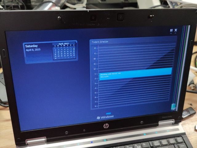 A fuzzy photo showing a laptop screen with the calendar from the previous image, and the "Windows is starting" text, but the calendar event is "Meeting with Steven Jobs"
