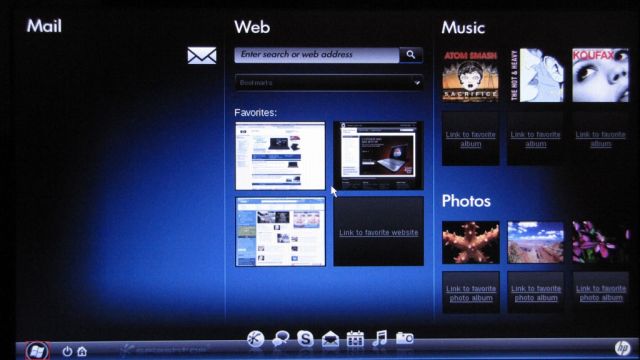 Photo of a laptop running HP QuickWeb, showing a "desktop" full of "widgets", such as a photo album and recently visited pages, as well as a summary of email messages, and a series of shortcut icons at the bottom to a web browser, music, photo viewer, Skype, chat app, and calendar
